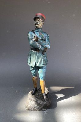 une statue représentant un homme coiffé d'un chapeau rouge, assis sur un rocher