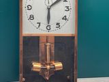 une horloge posée sur une table devant un mur vert