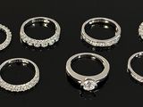 several different types of silver rings on a black surface