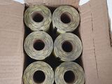 six rolls of thread in a box on a white surface