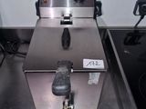 une photo d'une friteuse professionnelle posée sur un plan de travail en inox