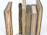 several old books are stacked on top of each other on a white surface