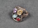 un gros plan d'une bague en argent sertie de pierres multicolores