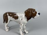 a figurine of a brown and white dog on a gray background