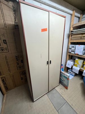 une armoire blanche dans une pièce où se trouvent des cartons par terre