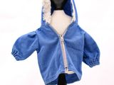 une petite poupée portant une veste bleue à capuche
