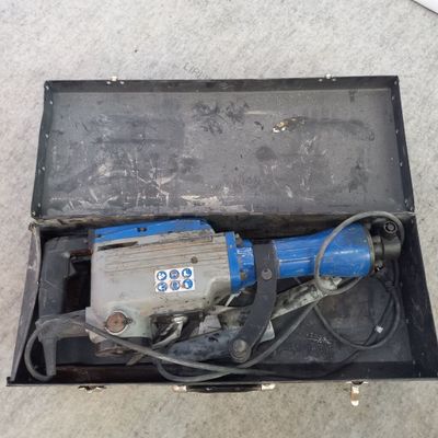 une petite perceuse électrique dans une boîte posée par terre