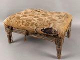 un vieux tabouret en bois avec une assise rembourrée de couleur beige clair