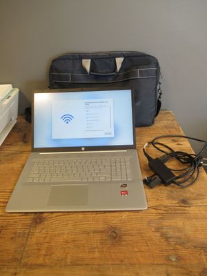 a laptop computer sitting on a wooden table with a bag