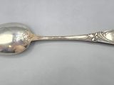 an antique silver spoon on a white surface with a silver spoon in the middle
