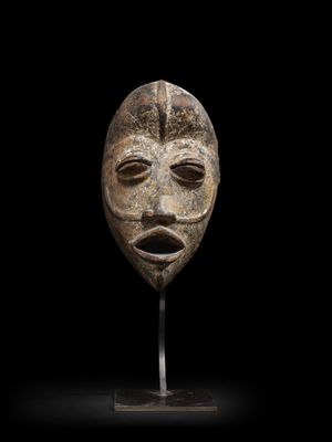 une image représentant un masque posé sur un support, sur fond noir