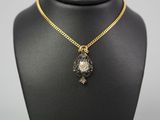 a gold necklace with a black and white stone pendant on a black mannequin