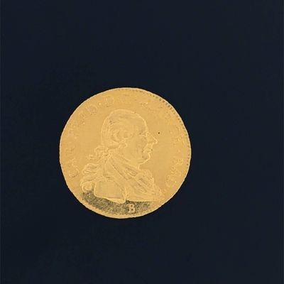 a close up of a gold coin on a black surface