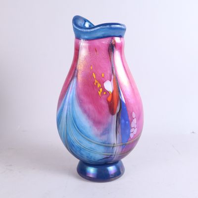 un vase en verre coloré posé sur une surface blanche