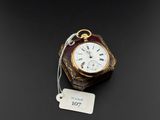 une montre de poche ancienne à laquelle est attachée une étiquette sur le côté