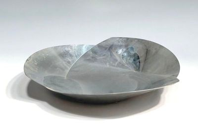 a large metal bowl with a curved edge on a white surface