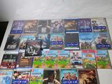 De nombreux DVD sont empilés sur une table devant un mur blanc.