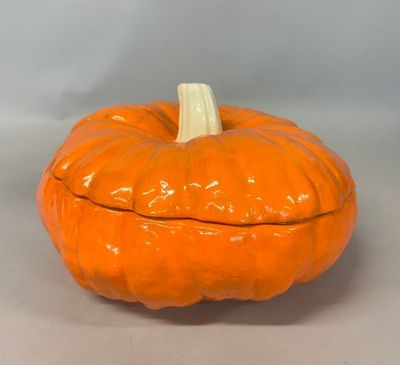 une citrouille orange au sommet blanc, posée sur une table