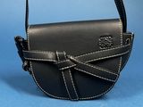 the small black purse is sitting on a blue surface