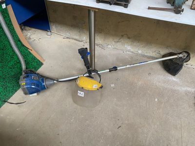 a blue and yellow corded string trimmer on the ground next to a blue and yellow cord trimmer
