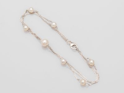a close up of a necklace with pearls on a white background