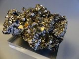gold and silver crystals on a metal stand on a white surface