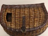 a wicker basket with a brown handle on a white surface