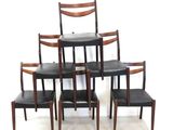 four chairs and a table in a room with a white wall
