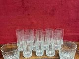 six verres transparents posés sur une table en bois près d'un mur rouge