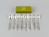 six spoons and a box of silverware sitting on a table