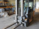 a forklift in a warehouse with pallets in the background