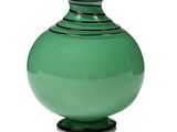 un vase vert posé sur une surface blanche