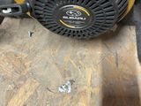 a close up of a yellow and black lawn mower on a wooden floor