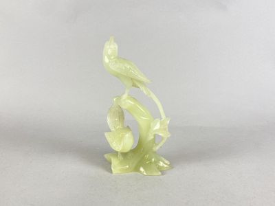 une petite statue représentant un oiseau perché sur une branche d'arbre