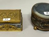 une petite boîte en or et une autre petite boîte en or posées sur une table