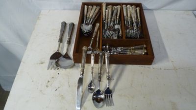 une boîte en bois contenant de l'argenterie, posée sur une table blanche