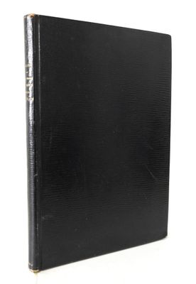 un livre noir aux bords dorés posé sur une surface blanche