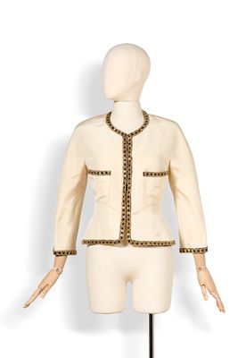 une photo d'un mannequin portant une veste blanche ornée de chaînes dorées