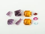 several different colored gems on a white surface with a white background