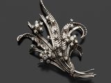 une broche en argent représentant des fleurs et des feuilles sur fond noir