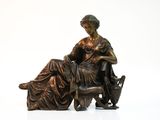 une statue en bronze représentant une femme assise sur une chaise