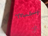 someone is writing on a red book on a marble table