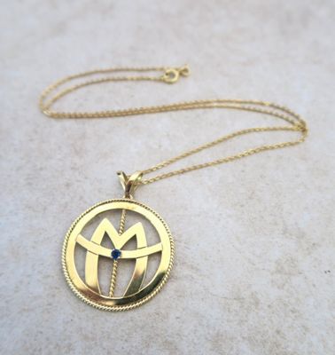 a close up of a gold necklace on a marble surface