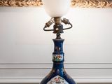 a lamp that is sitting on a table in front of a painting
