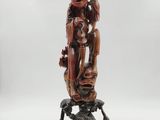 a wooden statue of a woman holding a child on a rock