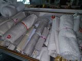 many rolls of white towels on display in a store