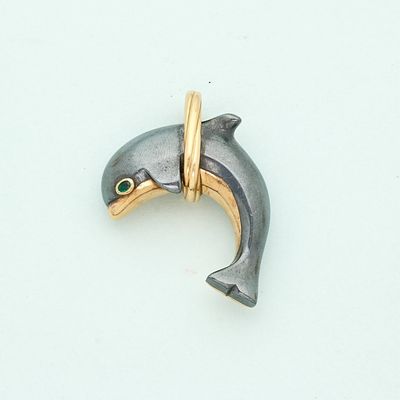 a silver and gold dolphin with green eyes on a white surface
