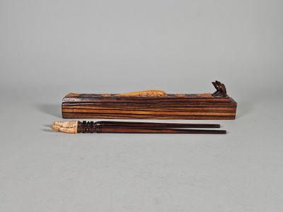 une image représentant une boîte en bois contenant deux baguettes et un crayon