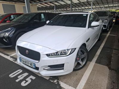 a white jaguar parked in a parking lot with other cars
