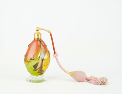 a small glass bottle with a pink handle on a white surface